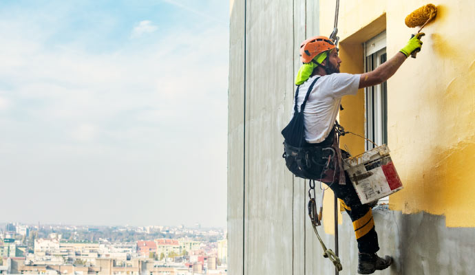 a painter painting the exterior of a Commercial building