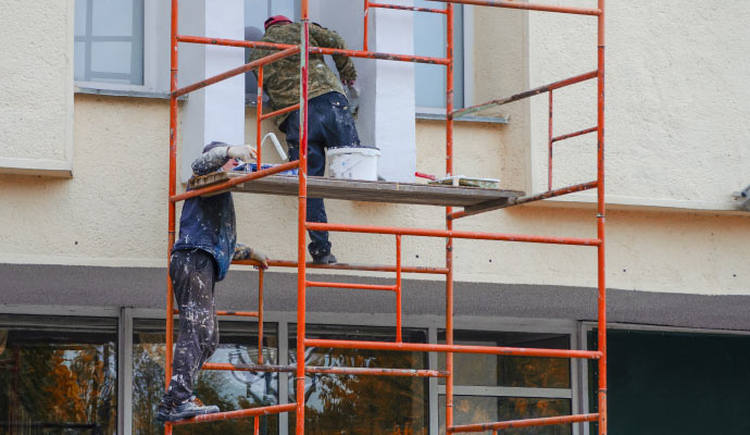 A couple of professionals painting the exterior of a Commercial space