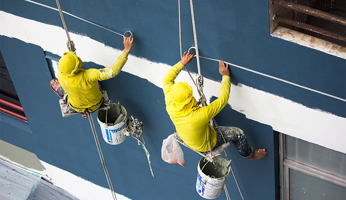 A couple of professionals painting the exterior of a commercial building