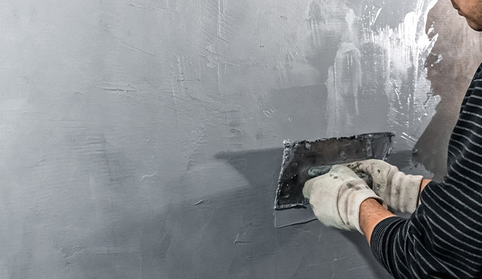 a person is applying cement coating to do mortar waterproofing